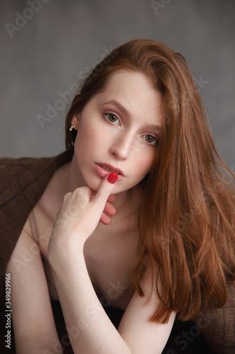 portrait of red-haired girl with a finger at the mouth