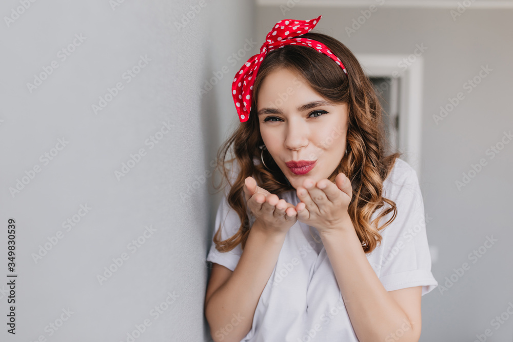 Cheerful girl with curly light-brown hair posing in studio. Adorable white young woman sending air kiss. Cheerful girl with curly light-brown hair posing in studio. Adorable white young woman sending air kiss.