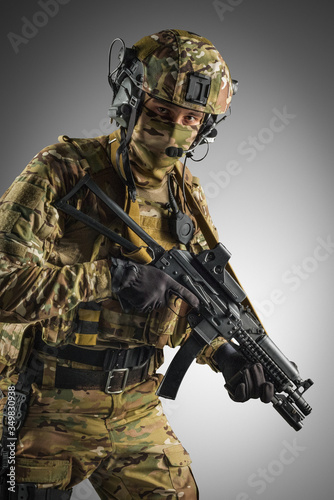 Soldier holding assault rifle. Uniform conforms to special services of the Russian Federation. Shot in studio. Isolated with clipping path on grey background © maximapryatin