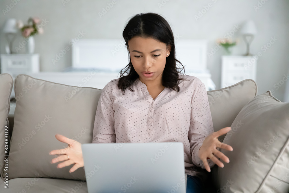African woman sit on sofa put notebook on lap has problems with device looks at screen feels annoyed by unexpected pc shut down unsaved documents turn off without warning, need repair service concept African woman sit on sofa put notebook on lap has problems with device looks at screen feels annoyed by unexpected pc shut down unsaved documents turn off without warning, need repair service concept