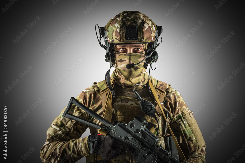 Fototapeta premium Soldier holding assault rifle. Uniform conforms to special services of the Russian Federation. Shot in studio. Isolated with clipping path on grey background