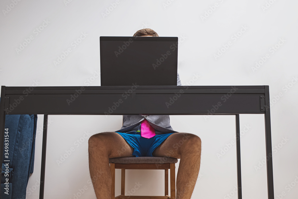Man wearing suit jacket and blue shorts while working with his laptop. - obrazy, fototapety, plakaty 