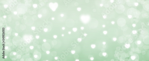 Glowing green bokeh background. Spring concept. Blurred bokeh circles and hearth shapes. Website banner. Celebration. Christmas.