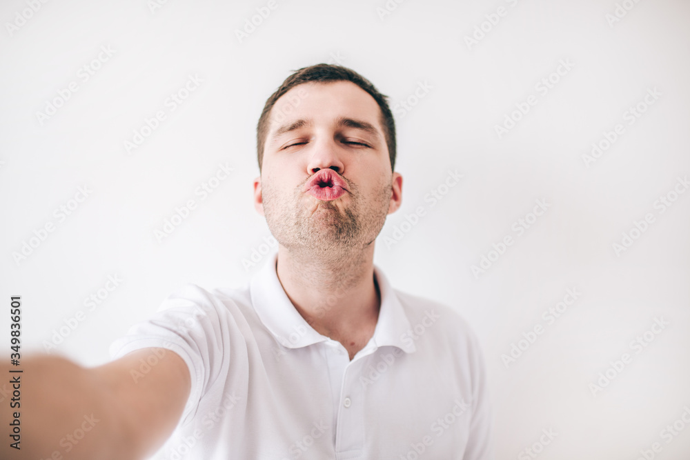 Young man isolated over white background. Ridiculous guy hold lips together like duck. Kissing mode. Funny posing on camera. Hold it with hand.