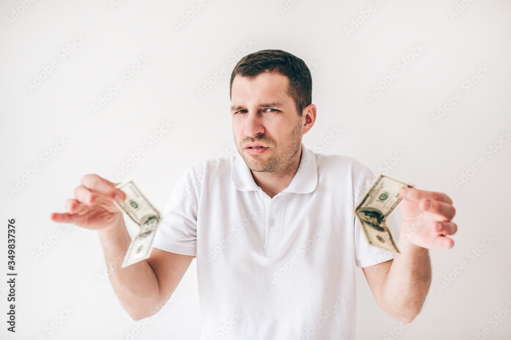 Young man isolated over white background. Confused guy hold two one hundred dollars bills in hands. Look at camera suspicious. Young man isolated over white background. Confused guy hold two one hundred dollars bills in hands. Look at camera suspicious.