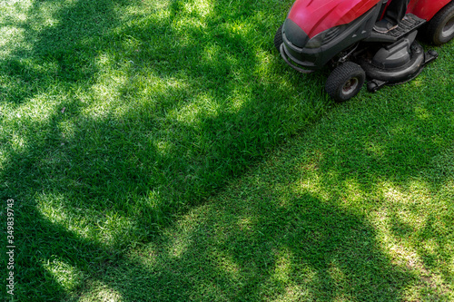 Top down above view of professional lawn mower worker cutting fresh green grass with landcaping tractor equipment machine. Garden and backyard landscape lawnmower service and maintenance