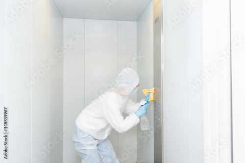 Concept coronavirus disinfection. People in hazmats making cleaning in lift apartment