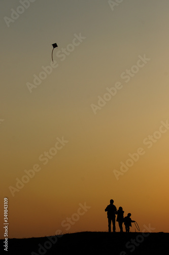silhouette of a family flying a kite.