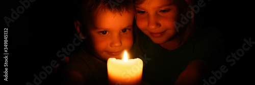 Wallpaper Mural happy kids siblings boy and girl admires a burning wax candle in the evening at home. banner Torontodigital.ca