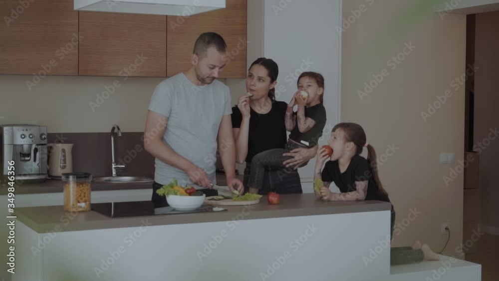 Happy family time with two daughters, cut vegetables for salads, cooking in the kitchen preparing a meal together Happy family time with two daughters, cut vegetables for salads, cooking in the kitchen preparing a meal together
