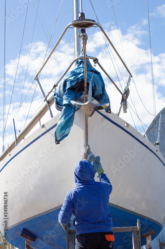 Portrait of unrecognizable mature man wearing protective mask repairing boat while working in yacht workshop, covering boat with pre-paint base coating, copy space