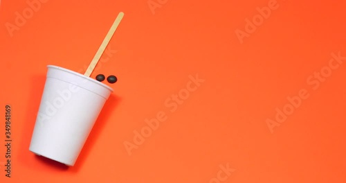Stop motion making a drink with sugar and coffee in a disposable bowl on a colored background.