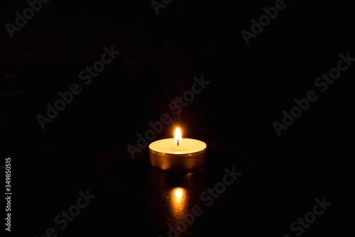 One burning candle on a black background.