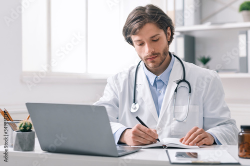 Male medical doctor making timetable for patients at office