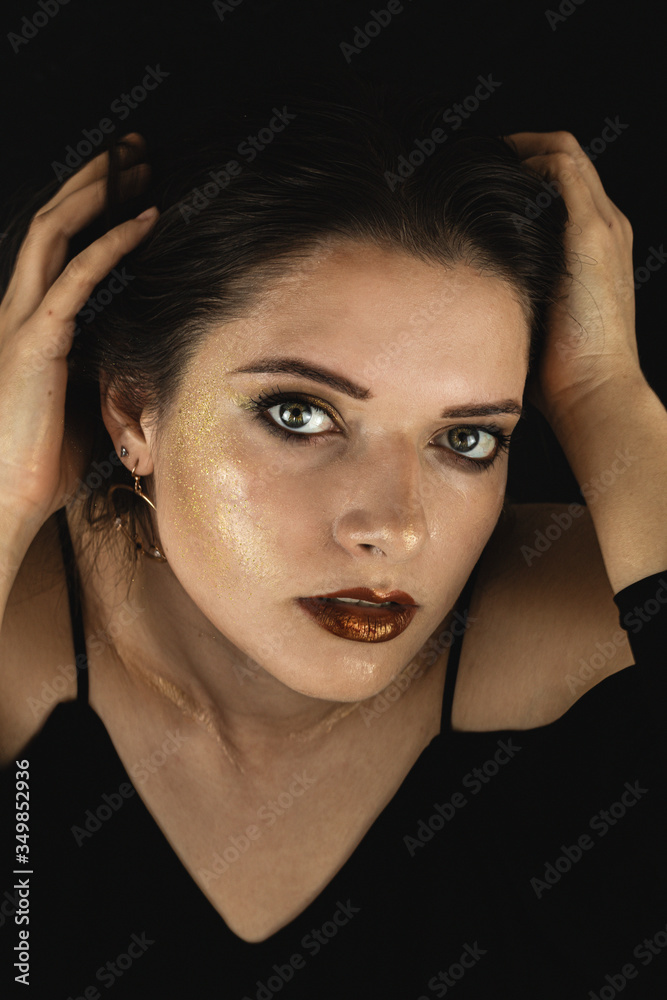 portrait of a young girl with gold makeup in black clothes on a black background portrait of a young girl with gold makeup in black clothes on a black background