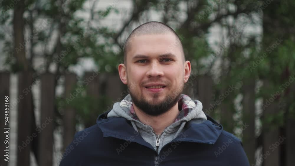 Brutal bald man smiling. Outdoor portrait of student worker with short hair Brutal bald man smiling. Outdoor portrait of student worker with short hair