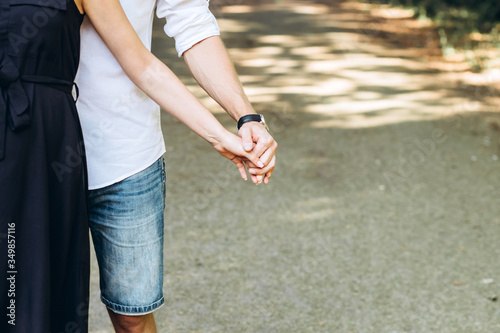 A young couple hold hands. lovers guy and girl walk in the summer in nature. The bride and groom. Hands close-up