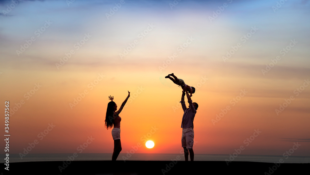 happy family playing on the beach at sunset