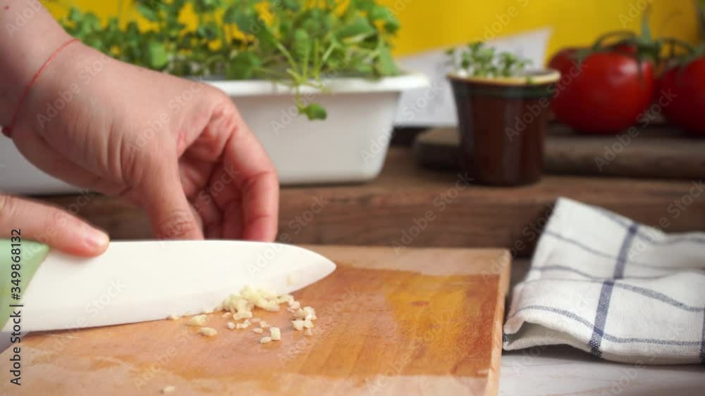 Person cut in small pieces fresh raw garlic to cook a dish