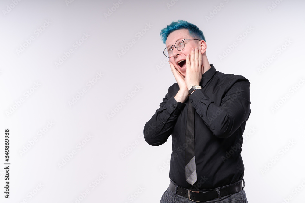 Young stylish european man with blue hair expressing amazement, shock and excitement, opening his mouth widely and touching his face Young stylish european man with blue hair expressing amazement, shock and excitement, opening his mouth widely and touching his face