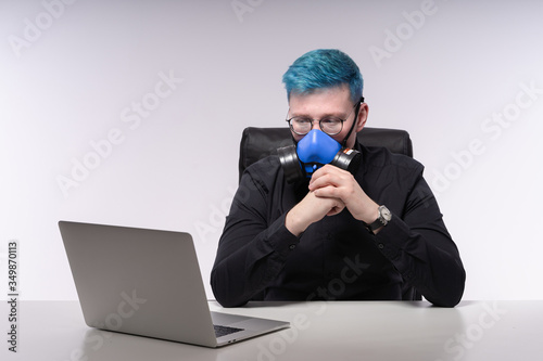 Quarantine work: young man in a face mask working remotely, looking seriously on a laptop, studio shooting © Tkachenko Alexey