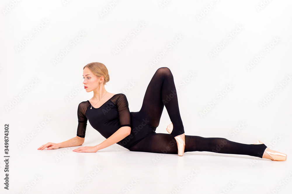 The concept of rhythmic gymnastics. Caucasian model at full height with fair hair in black swimsuit lies The concept of rhythmic gymnastics. Caucasian model at full height with fair hair in black swimsuit lies