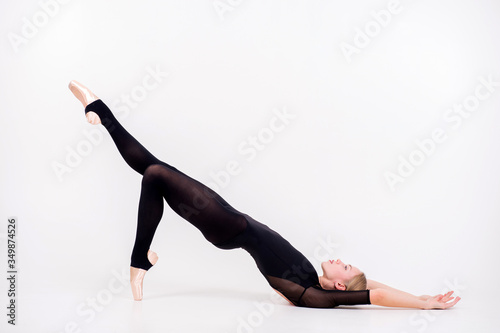 Attractive young female gymnast with pale skintraining calilisthenics exercise on a white studio background