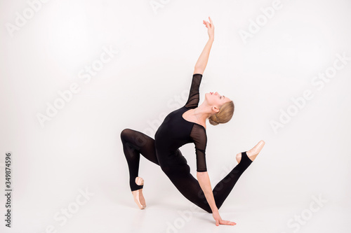 Attractive young female gymnast with pale skintraining calilisthenics exercise on a white studio background