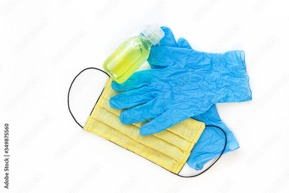 Yellow medical mask and blue gloves and yellow sanitizer to protect health from the virus on a white isolated background Yellow medical mask and blue gloves and yellow sanitizer to protect health from the virus on a white isolated background