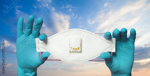 Hands wearing doctor gloves showing n99 or ffp3 protective mask against sky clouds background, safety and virus protection concept photo