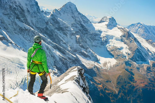 Climber at the top of a mountain peak in Alps