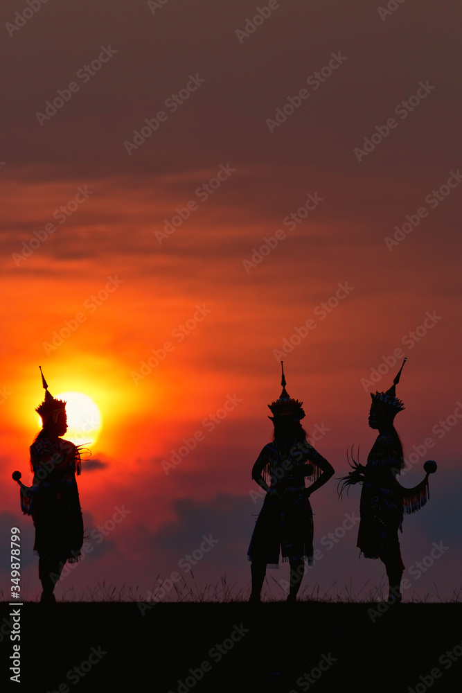 Φωτογραφία The black silhouette of three Manohra actors dancing in the park in the evening