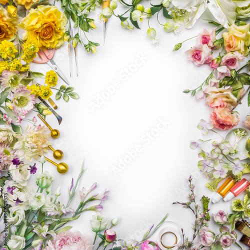 Top view of round frame with decoration artificial flowers  branches  leaves  petals  instruments and paint. isolated on white background.  