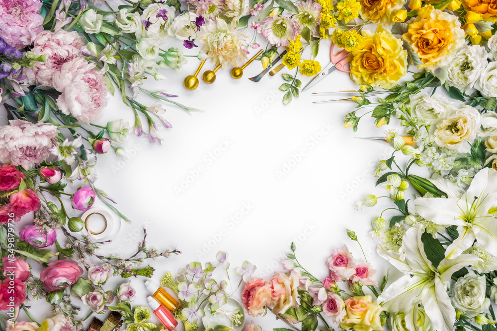 Top view of round frame with decoration artificial flowers, branches, leaves, petals, instruments and paint. isolated on white background. 
