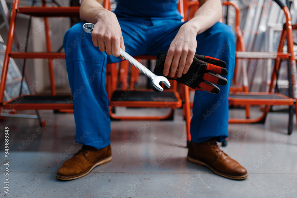 Male employee in uniform holds wrench, tool store Male employee in uniform holds wrench, tool store
