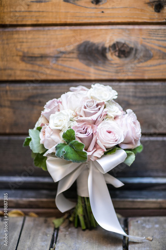 pink and white wedding bouquet leaning on wood wall