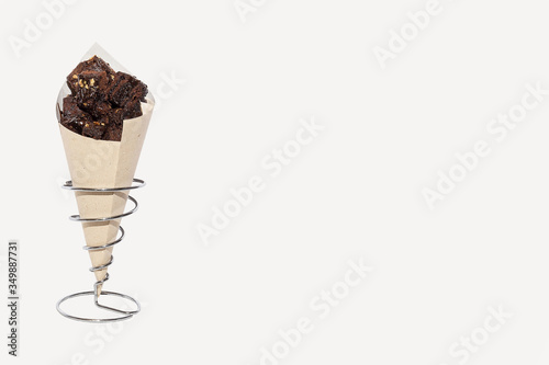 Delicious brownie cone dessert presented on a metal stand. Off-white background with copy space. Selective focus