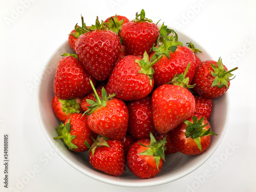 Plump ripe fresh strawberries in a white bowl on a plain white background.