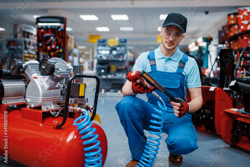 Worker poses with pneumatic nailer in tool store photo