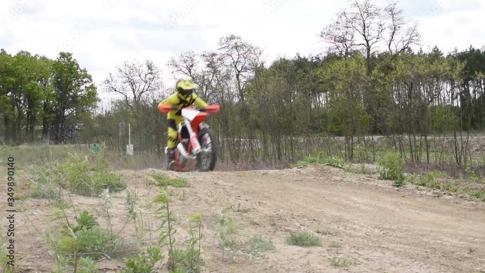 Boys in suits and helmets on motocross bikes practising jumps on an outdoor track Boys in suits and helmets on motocross bikes practising jumps on an outdoor track