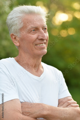 Portrait of beautiful smiling senior man posing in summer park