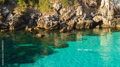 unknown person swimming in turquoise water in menorca, cala macarelleta (balearic islands, spain)
