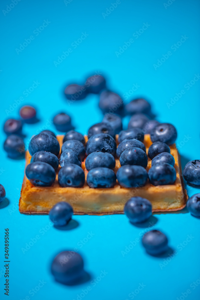 Sweet Homemade waffles with fresh raspberries, blueberries and cream on wooden table background Sweet Homemade waffles with fresh raspberries, blueberries and cream on wooden table background