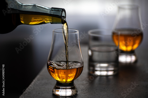 Fototapeta Pouring in tulip-shaped tasting glass Scotch single malt or blended whisky