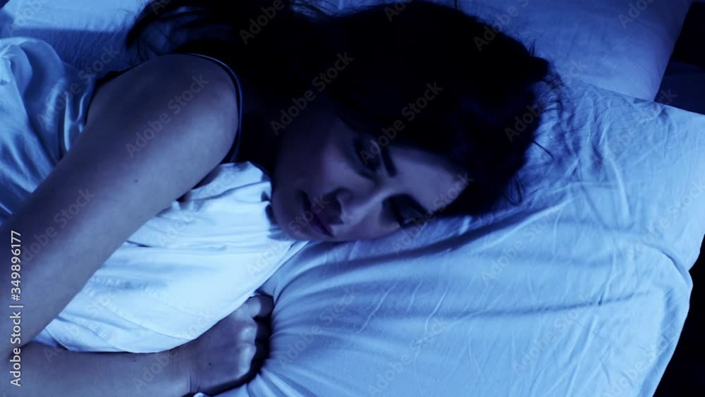 Closeup of woman at night in bed unable to sleep suffering of insomnia slow motion
