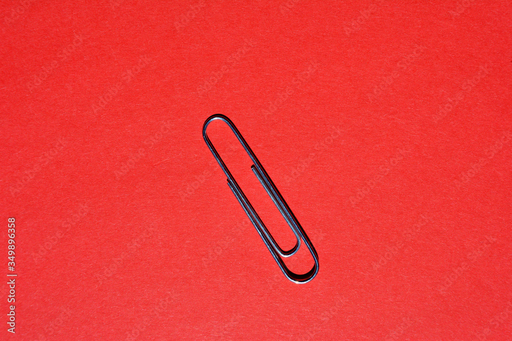 Metal paper clip isolated on red background with copy space Metal paper clip isolated on red background with copy space