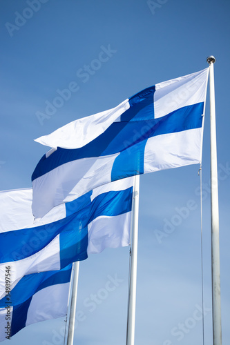 Three finnish national flags on the wind against the blue sky