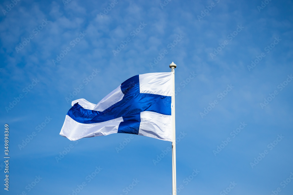 Fototapeta premium Finnish national flag on the wind against the blue sky