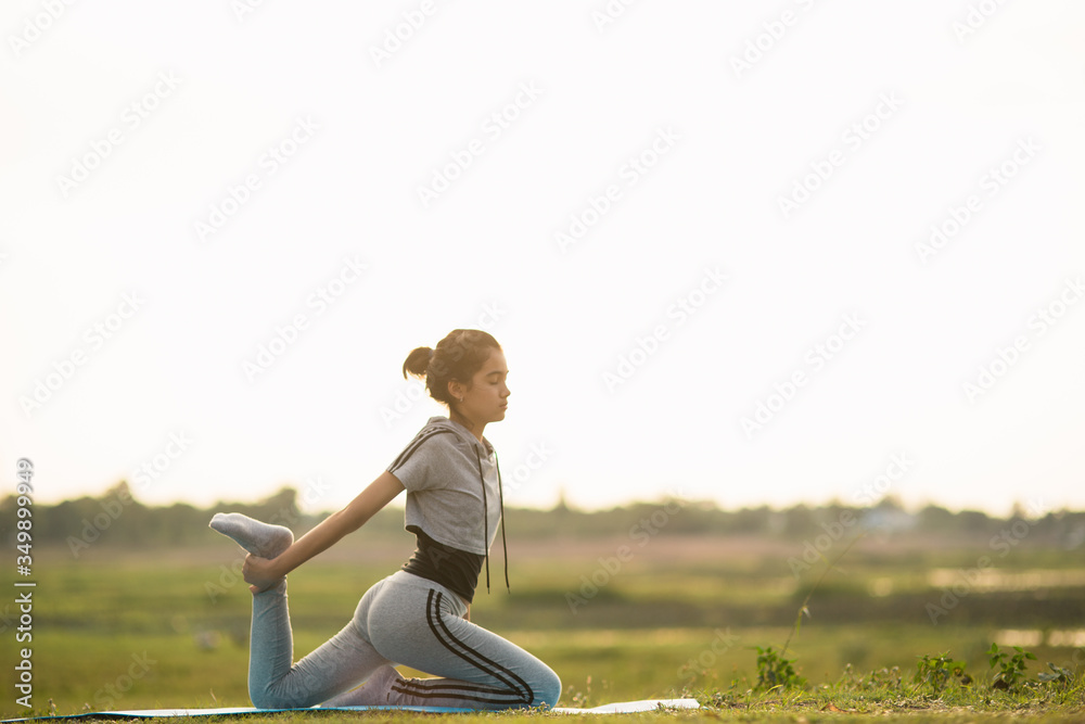 Portrait of a Young Woman performing Yoga outside in sunny bright light.