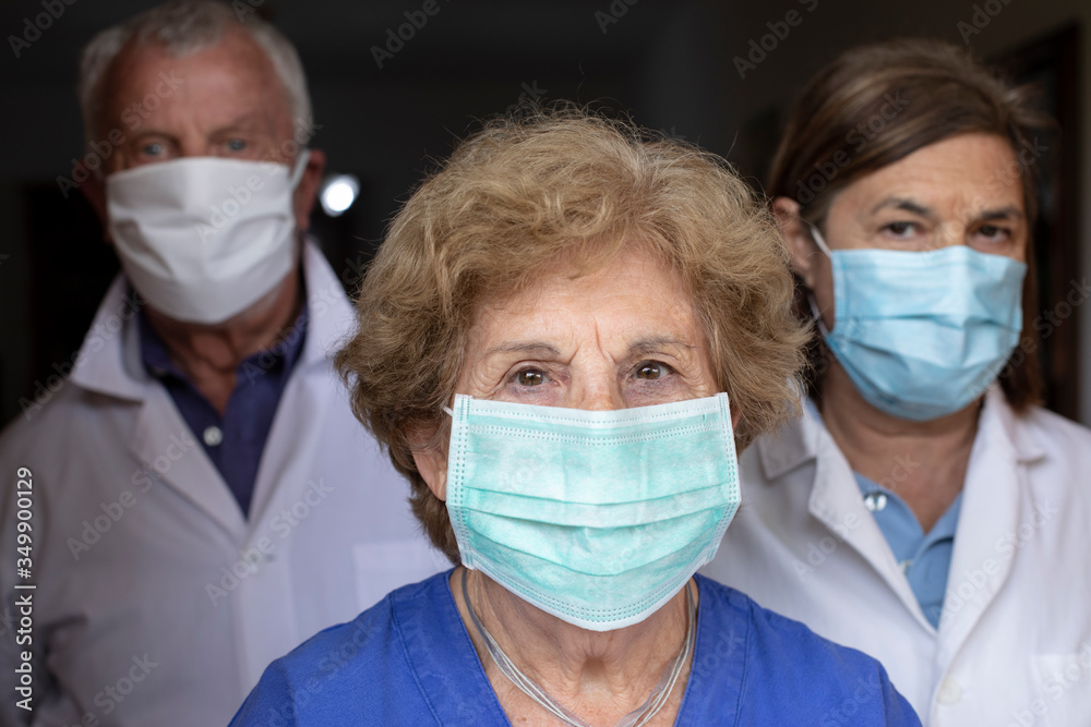 gruppo di tre medici esperti con mascherina e camice bianco che guardano decisi, isolati su sfondo nero gruppo di tre medici esperti con mascherina e camice bianco che guardano decisi, isolati su sfondo nero